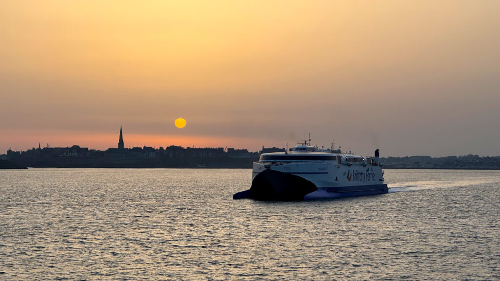 Le catamaran Voyager (Brittany Ferries) est photographié, sous le soleil levant, peu après son appareillage de Saint-Malo.