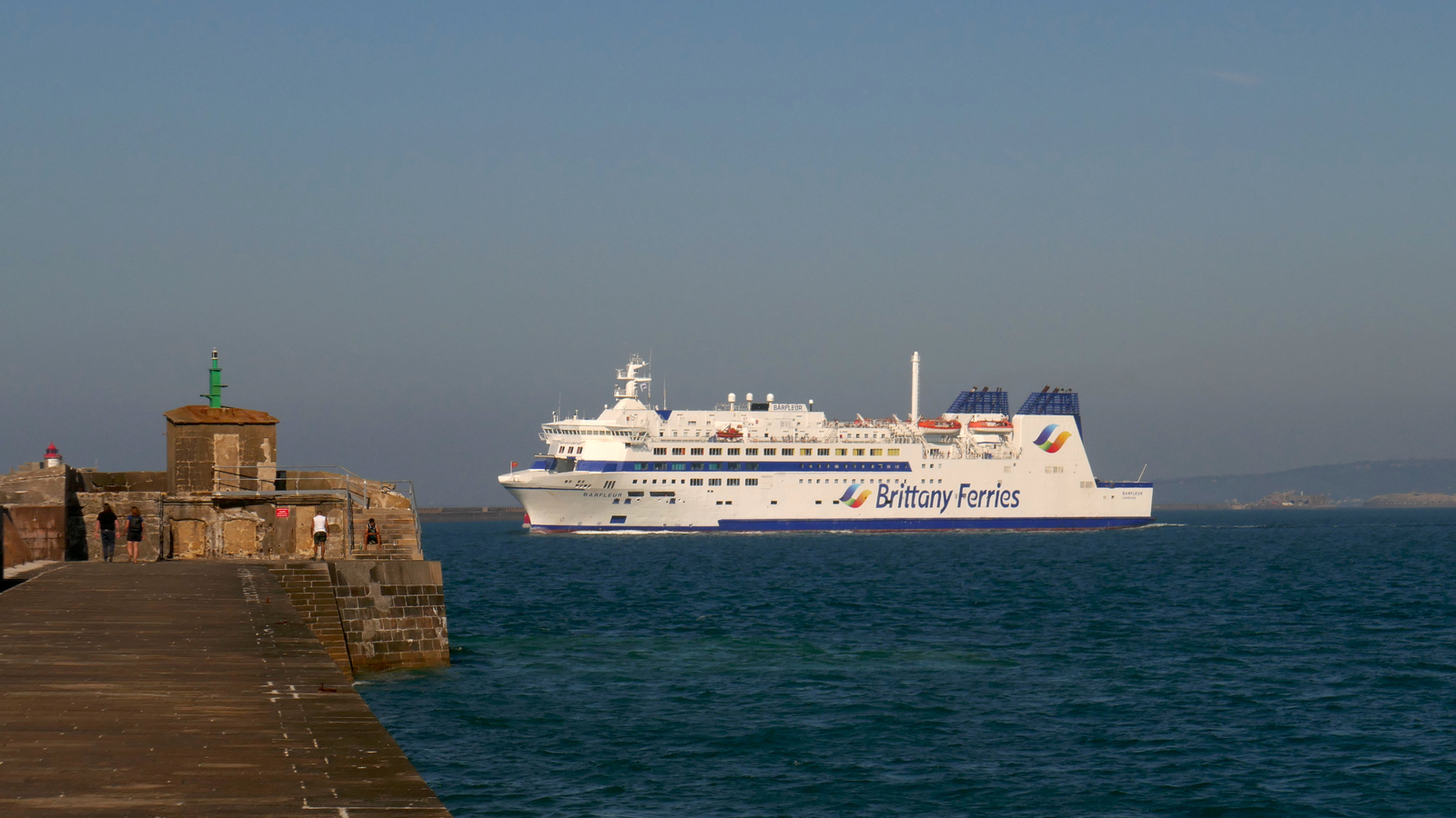 Le navire mixte M/V Barfleur de Brittany Ferries s'apprête à passer la digue de Querqueville, qui marque la sortie de la rade de Cherbourg.